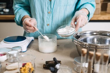 Person wearing gloves adds white powder to liquid mixture among professional laboratory equipment. clean beauty lab, sustainable apothecary, eco-professionalism, sterile skincare making