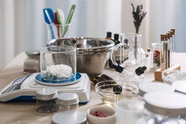 Katı yağlı cam deney şişesi, laboratuvar ekipmanları ve malzemeleriyle çevrili dijital ölçekte bulunur. Özel yağ karışımı, özel yapım yüz yağları, kişiselleştirilmiş cilt bakımı, hedeflenmiş güzellik yağları.