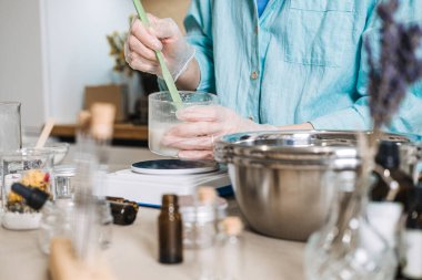 Eldivenli kişi, dijital ölçekte cam kapta sıvı karıştırmak için spatula kullanır. Cilt bakımı mikro doz, aktif bileşenler, kesin formülasyon, bitkisel etki