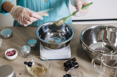 Kişi yeşil spatulayı metal kasenin üzerinde kozmetik kavanozlarla çevrili kahverengi tozu tutmak için kullanır. Yavaş yaşayan eczacı, düşünceli yaratım süreci, sağlık çalışma alanı, güzellik işçiliği