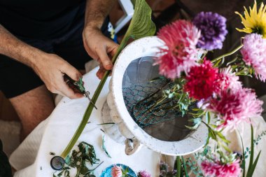 Eller uzun yeşil sapı kırpma makası ile pembe astar içeren beyaz taş vazonun yanında. Nostaljik çiçek kokuları, çiçekleri tetikleyen anılar, eski kokulu bahçeler, çiçek düzenlemeleri..