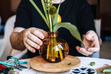 Cam vazoda insan yaprağına ve sarı meyveye dokunur. duyusal bitki terapisi, dokunsal çiçek bahçesi, duyusal botanik köşesi, topraklama çiçek dokusu..