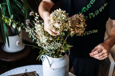 Çiçekçi, ortanca ve yaprak dalları ile kaliteli bitki örtüsü düzenlemesi yapıyor. Çiftlik evi şık çiçekleri, kır çiçekleri ev dekorasyonu, klasik vazo, kır tarzı iç mekan, pejmürde şık