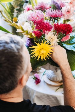 İnsanlar paskalya çiçeklerini büyük yeşil yapraklarla taştan vazoya koyuyorlar. Yavaş çiçek hareketi, mevsimlik çiçekler, gladyatörler ve astörler, çiftlikten vazoya, yerel kaynaklar, bilinçli tüketim
