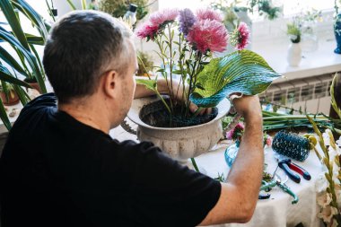 Paskalya çiçekleri ve yeşil haç yaprağını beyaz dekoratif kaseye yerleştirir. Çiçek meditasyon pratiği, yavaş düzenleme çiçekleri, düşünceli çiçekçilik, zen çiçeği terapisi, meditasyon çiçekleri tasarımı