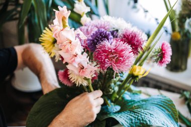 İnsanların elleri pembe gladiolusu dikkatlice büyük renkli çiçek aranjmanlarına yerleştirir. Çiçek düzenleme süreci, dokunsal sanatçılık butik çiçekçi stüdyosu, bağımsız yaratıcı.