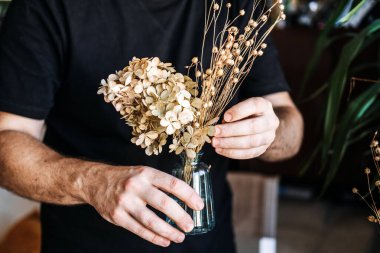 Kurutulmuş ortanca ve linum saplı mavi cam vazo. Keten buket, doğal dekor, toprak tohumu kapsülleri, basit demet.