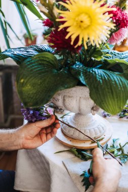 İnsan elleri çiçek sapını budama kabının yanında bahçe budayıcıları ile budarlar. Çiçek düzenleme süreci, dokunsal sanatçılık butik çiçekçi stüdyosu, bağımsız yaratıcı.