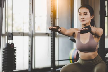 Genç Asyalı kadın spor salonunda jimnastik yapıyor sporcu kızla azimli bir atlet spor eldiveni giyiyor ve çekici bir bayan spor salonunda popo egzersizi yapıyor.