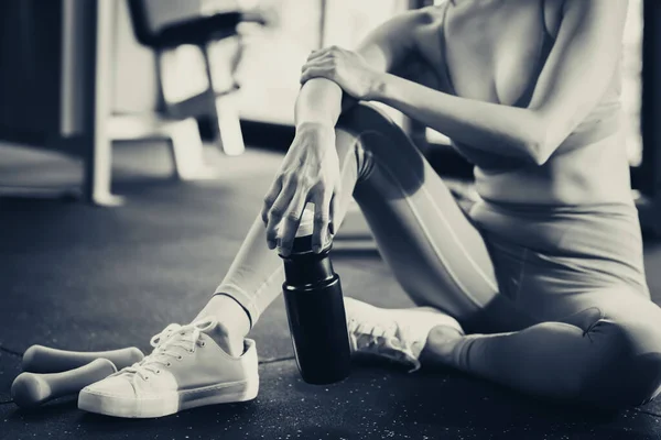 Sport woman workout at fitness center with relax and taking a rest Beautiful girl holding protein shake bottle after exercise at gym Healthy lifestyle Fitness and sport concept with black and white