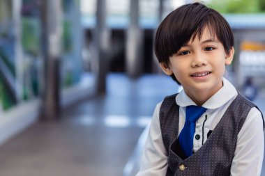 Gülümseyen yüzlü yakışıklı Asyalı çocuk sevimli bir yüzü var. Ailesinin ilk oğlu. Ceket ve kravat takıyor, zeki ve zeki görünüyor.