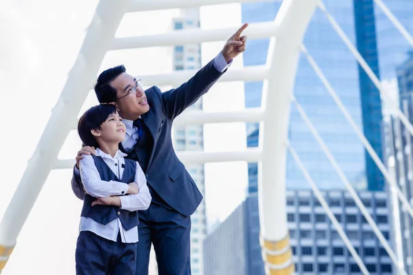 Business father showing heritage of property to his son that young boy will be heir. Little child is inheritor of property in the future. Businessman pointing finger to his property for showing son