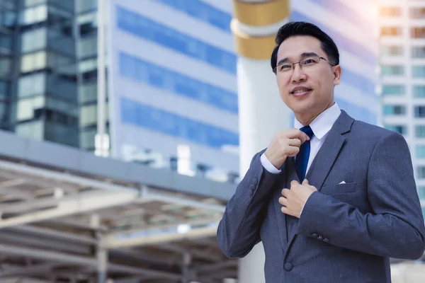 Portrait happy businessman in city Happy leadership business man get confident and determined He wear suit, necktie Handsome asian white collar worker guy stand in metropolis with building background