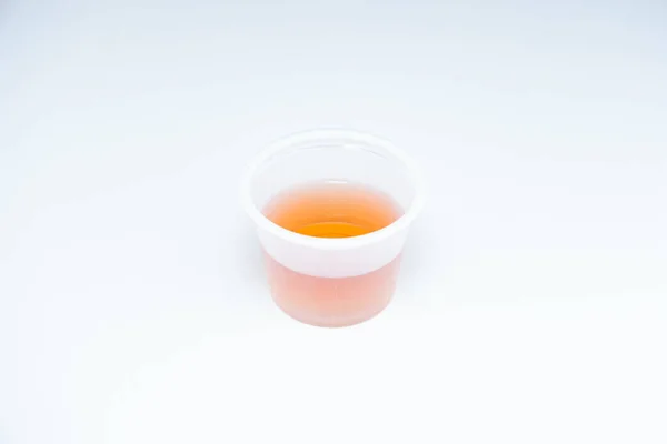 Μικρό Διάφανο Πλαστικό Κύπελλο Πόσιμο Φάρμακο Πορτοκαλί Χρώμα Υγρό Απομονώνονται — Φωτογραφία Αρχείου