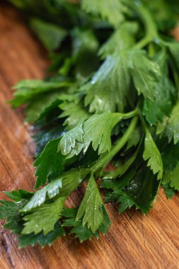 Taze yeşil ıslak kereviz yaprakları ahşap mutfak tahtasına yakın çekim..