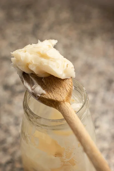 Mutfaktaki cam kavanozun üzerinde tahta kaşık üzerinde çiğ domuz yağı yakın çekim üst görüntü.