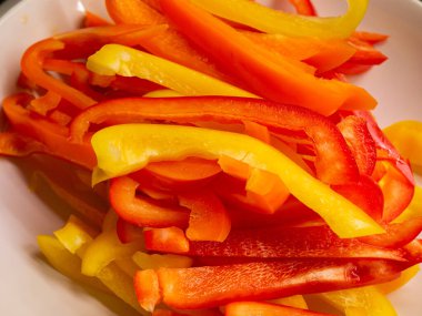 Dilimlenmiş kırmızı turuncu ve sarı tatlı biber şeritleri, yakın çekim..