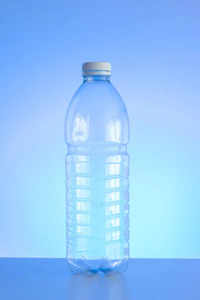 透明的空塑料瓶 红色瓶盖与浅蓝色底色垂直枪弹隔离 — 图库照片