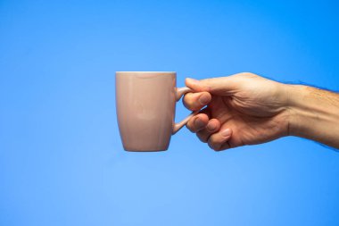 Kafkas erkek eli mavi arka planda izole edilmiş seramik jenerik kahve kupası tutuyor..