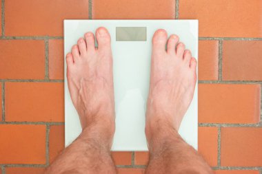 Beyaz erkek çıplak ayak dijital ağırlık ölçeğinde duruyor..