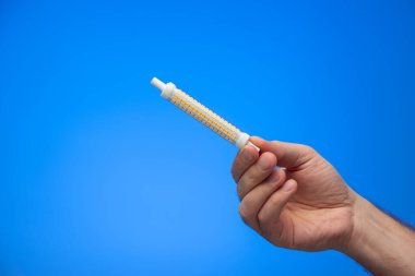 Kafkas erkek el stüdyosu tarafından tutulan uzun silindirik ampuller mavi arkaplandan izole edilmiş..