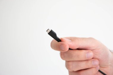 Beyaz arka planda izole edilmiş beyaz erkek eli tarafından tutulan USB kablo reklam konnektörü.