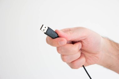 Beyaz arka planda izole edilmiş beyaz erkek eli tarafından tutulan USB kablo reklam konnektörü.