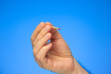 Kafkas erkek el stüdyosu eliyle mavi üzerine izole edilmiş yeni bir kibrit çöpü..