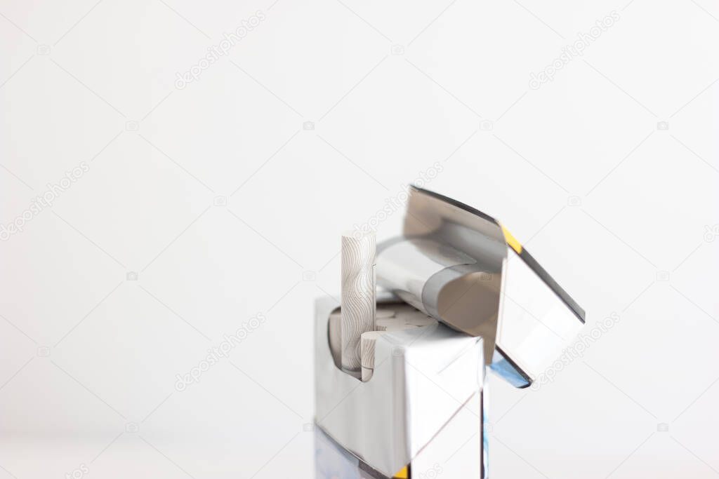 Opened packet of nondescript generic cigarettes with four pieces sticking out close up studio shot isolated on white.