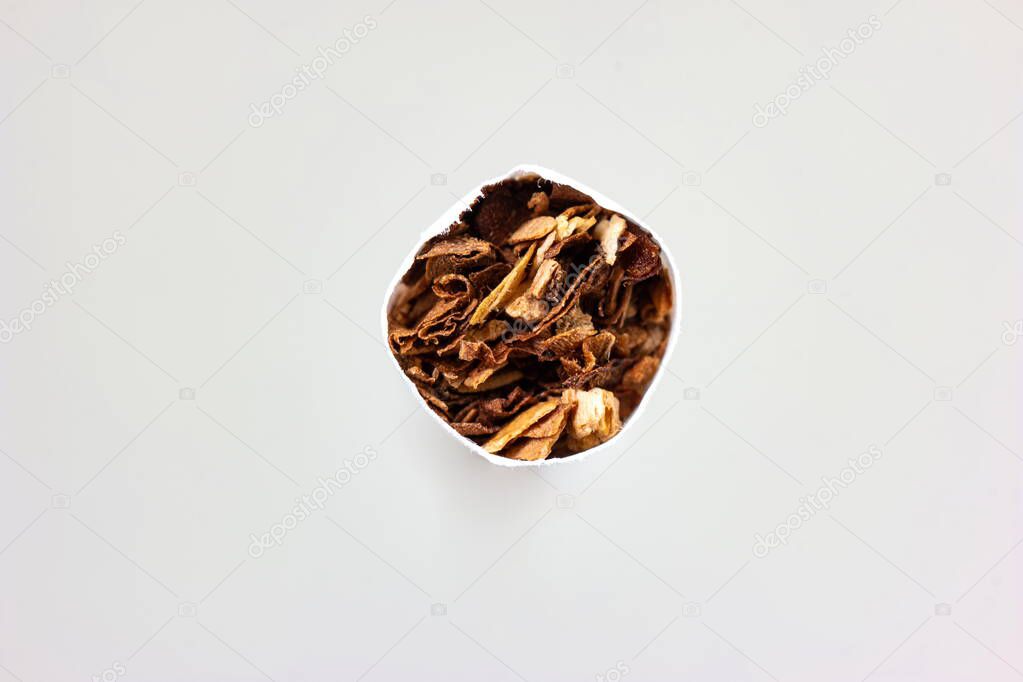 Single unlit cigarette stick macro detail shot of ground tobacco leafs front view isolated on white.