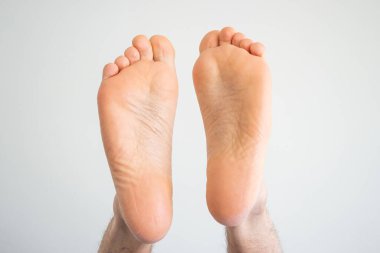 Beyaz tenli erkek, çıplak ayakla üstten görünüyor. Yakın çekim, beyaz üzerine izole edilmiş..