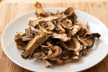 Kurumuş kurutulmuş mantarlar beyaz tabak ahşap arka planda yakın plan çekimi