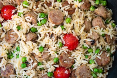 Eastern rice sausage peas and cherry tomatoes dish top view close up macro shot.