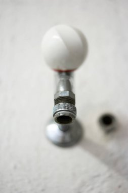 Eski moda metal ve beyaz ebonit duvar musluk suyu musluğu umumi çamaşır odasının içine monte edilmiş düşük açılı sığ alan derinliği yakın çekim..