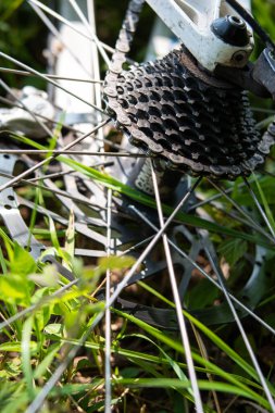 Mountain bicycle rear gear cassette and chain laying on the grass close up shot no people.