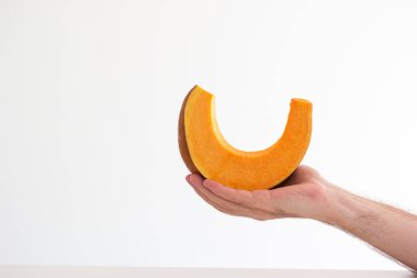 Beyaz erkek eli tarafından elde tutulan taze çiğ balkabağı dilimi. Stüdyoyu kapat, beyaz üzerine izole edilmiş..