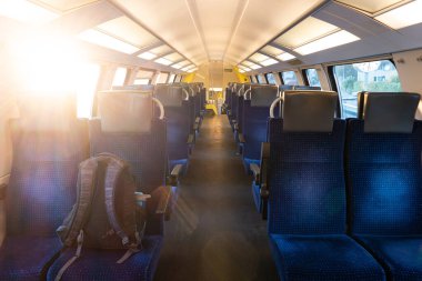 Boş bir tren koltuğunda gezgin çantası. Kulübede delici güneş ışınları var, insan yok..