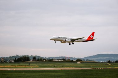 Zürih Havaalanı, İsviçre, 26 Eylül 2025. Helvetic Havayolları ticari yolcu uçağı havaalanı pistine iniyor. Yakın çekim, telefoto yan görüş, çok alçak irtifa, insan yok.