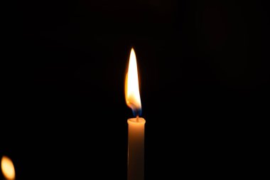 Zifiri karanlık zeminde yanan bir mum. Yaklaş, makro çekim, insan yok.