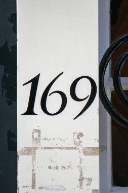 Dış tuğla duvarda 169 numaralı ev. Ön manzara, yakın çekim, insan yok.