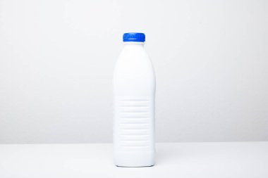 Mavi vida kapaklı beyaz plastik bir şişenin temiz, dikey görüntüsü. Stüdyo çekimi, beyaz, insan yok.