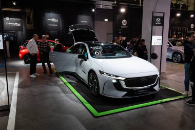 Zürih Oto Fuarı, İsviçre, 31 Ekim 2025. Auto Zürih Show 'da yeni, elektrikli Mazda 6e veya EZ-6 sedan. Geniş açı, ön görüş, insanlar oradan geçiyor.