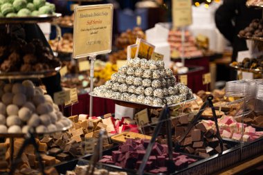 Zürih, İsviçre, 20 Kasım 2025. Çikolatalı yer mantarı çeşitleri ve el yapımı İngiliz şekerlemeleri Noel marketlerinde ya da tezgahlarda sergileniyor. Yakın çekim, alanın derinliği