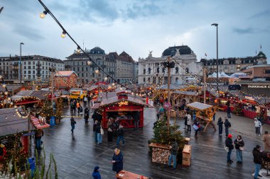 Zürih, İsviçre, 20 Kasım 2025. İnsanlar Sechselautenplatz Noel pazarındaki dükkanları ve tezgahları ziyaret ediyor. Bulutlu bir akşam, asılmış bir sürü Noel ışığı