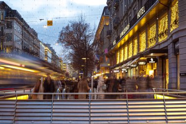 Zürih HB, İsviçre, 5 Aralık 2025. Bulanık, Bahnhofplatz yaya geçidindeki insanların uzun pozu. Akşamüstü, Noel ışıkları ve süslemeleri.