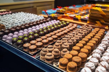 Vitrindeki el yapımı çikolatalı trüf ve pralinlerin çeşitliliği. Kapat, kimse yok.