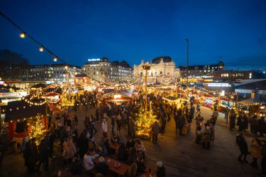 Zürih, İsviçre, 17 Aralık 2025. Akşamları bir sürü insan Noel marketlerini ve dükkanları ziyaret ediyor. Ultra canlı açı görüntüsü, büyük süslü Noel ağacı ve ışıklar.
