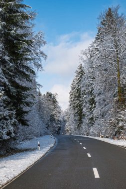 Kış yolu karla kaplı bir ormanın içinden geçiyor. Geniş açı, araba yok, insan yok.