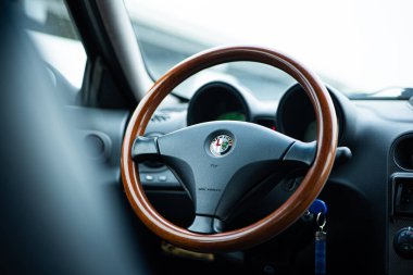 Arad, Romanya, 22 Şubat 2026. Alfa Romeo 156 gösterge panelinin yakın çekimi, üç dilli ahşap direksiyon ve marka logosu var.