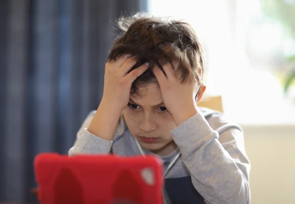 Young zmatený chlapec, při pohledu na tabletu — Stock fotografie